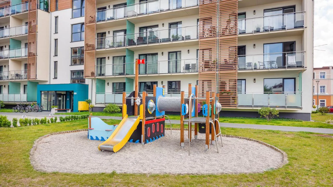 Kolorowy plac zabaw z huśtawkami i zjeżdżalnią między budynkami