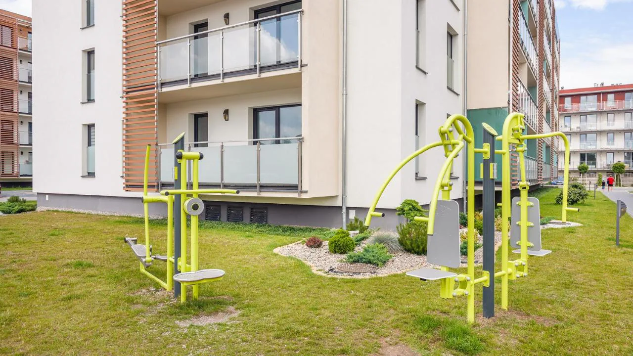 Plenerowe urządzenia do ćwiczeń na zielonym terenie osiedla
